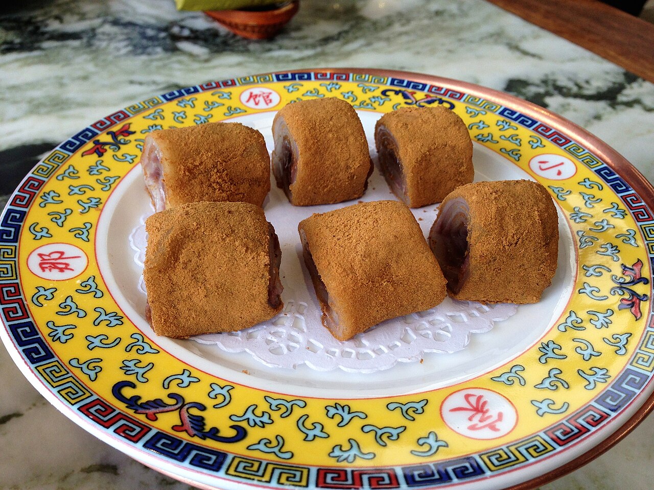 Soybean-flour-coated lvdagun rolls with dark filling on a patterned plate