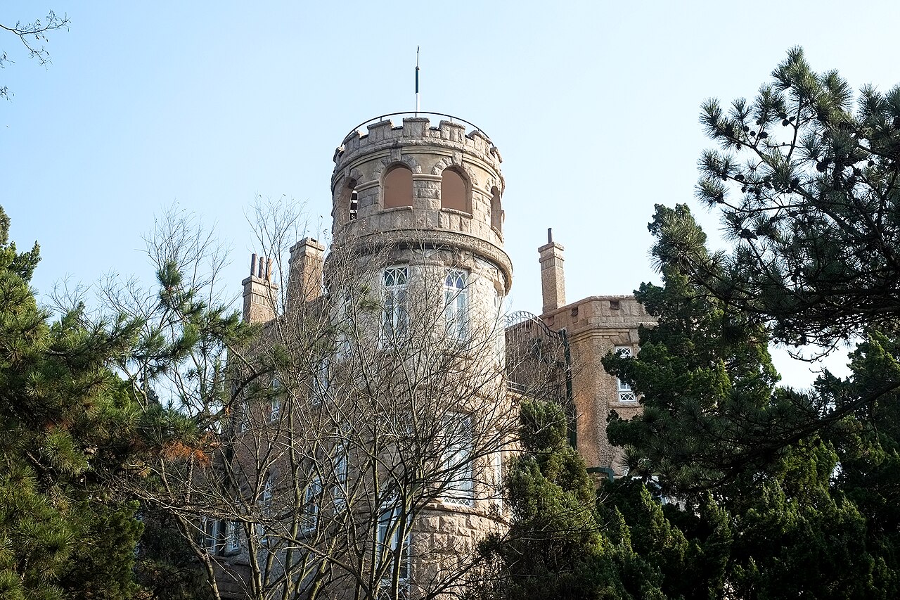 Stone tower of Huashi Lou framed by trees in Qingdao Badaguan