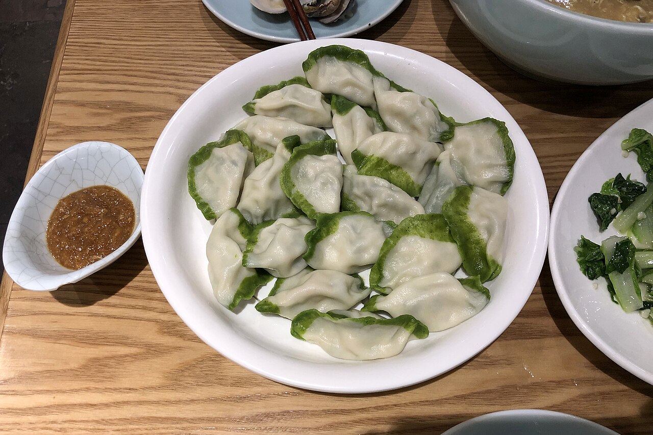 Plate of mackerel-filled dumplings with green-edged wrappers photographed in Qingdao