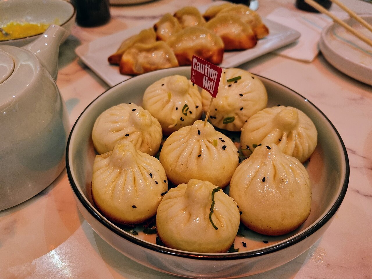 Shengjianbao pan-fried buns topped with sesame and scallions on a plate
