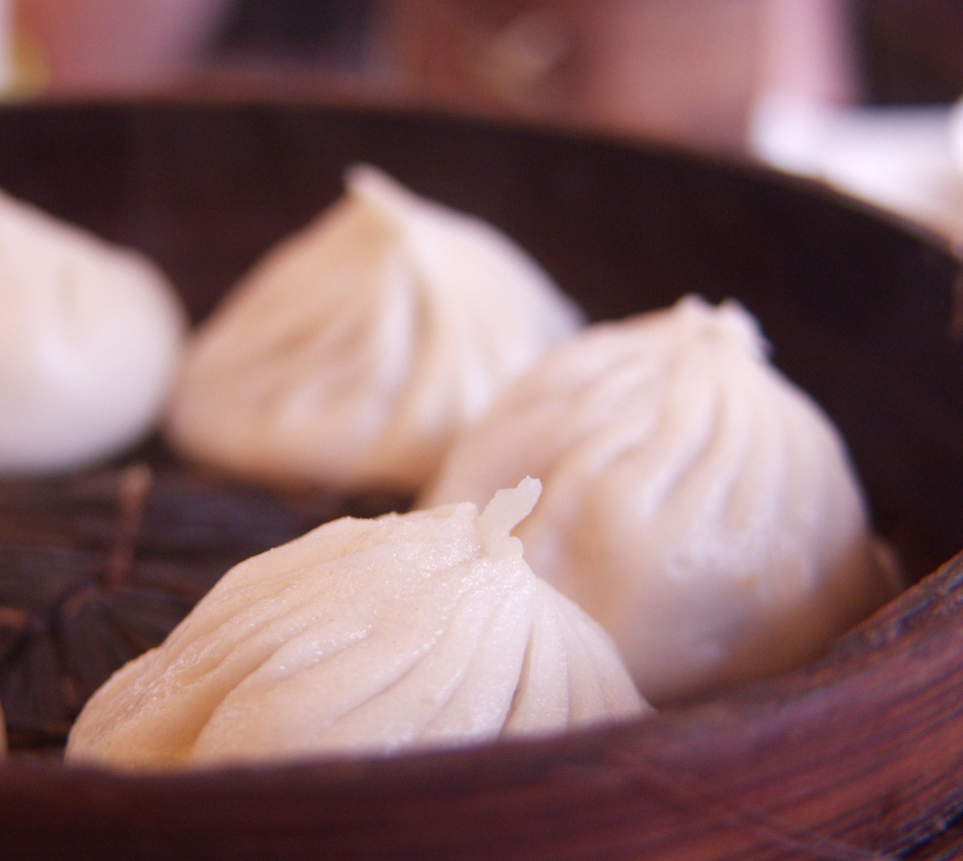 Pleated xiaolongbao soup dumplings in a bamboo steamer